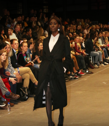 Model in a black tailored coat during a fashion presentation